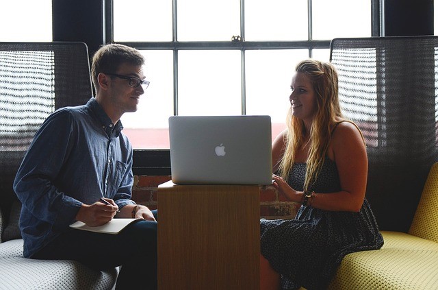 A man and a woman sitting in front of a laptop talking, in one of the best places to start a business in South Florida.