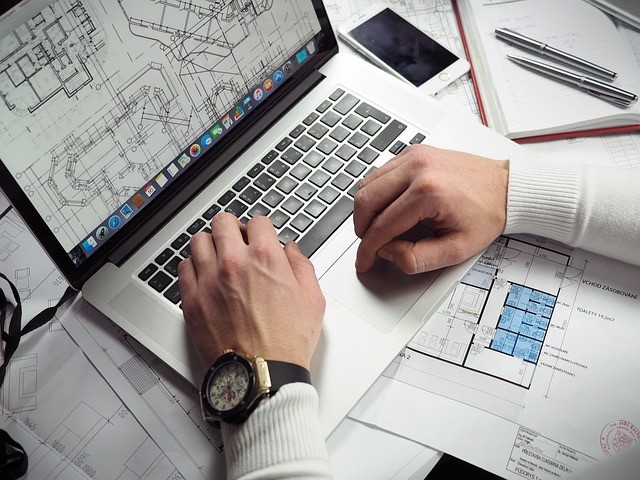 A person looking at building plans on a laptop.